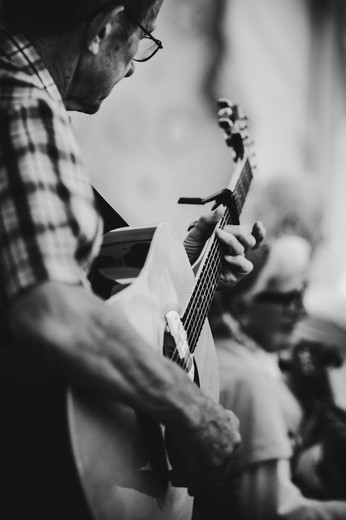 Artistic black and white photo capturing a guitarist in an intimate performance.