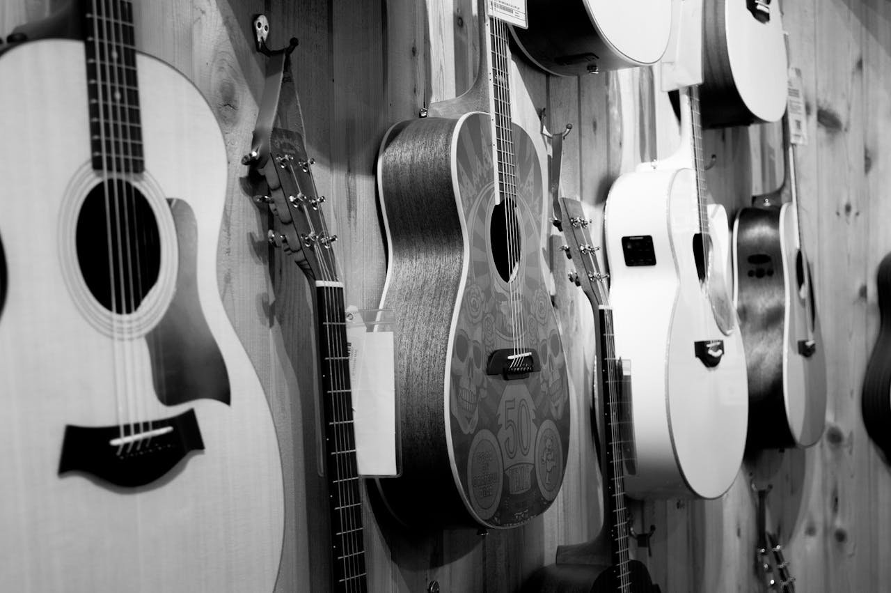 Wall-mounted acoustic guitars in a music shop, black and white photo.